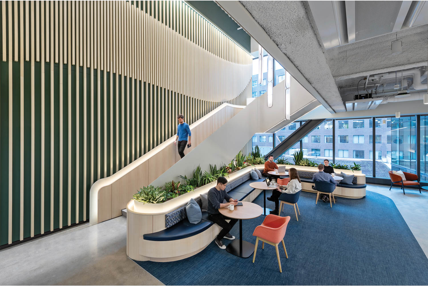 a person walks down a white staircase into an office common area