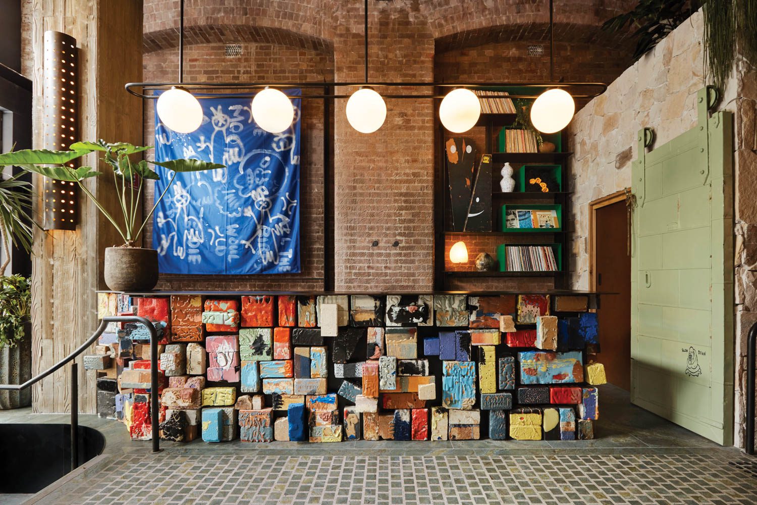 At the Ace Hotel Sydney by Flack Studio, the reception desk is a James Lemon installation of polychrome ceramic bricks—a nod to the neighborhood’s history of pottery production—backed by a Jason Phu wall hanging.