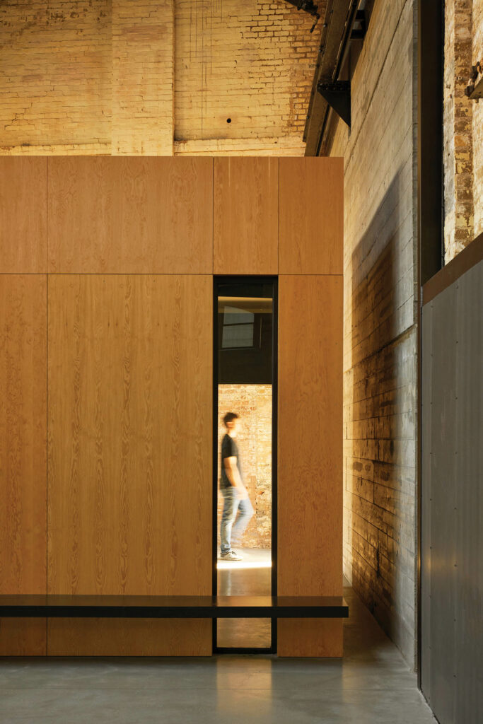 a person in a narrow doorway through a wood wall