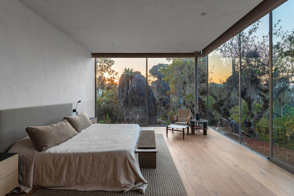 a bedroom with two walls of windows at sunset