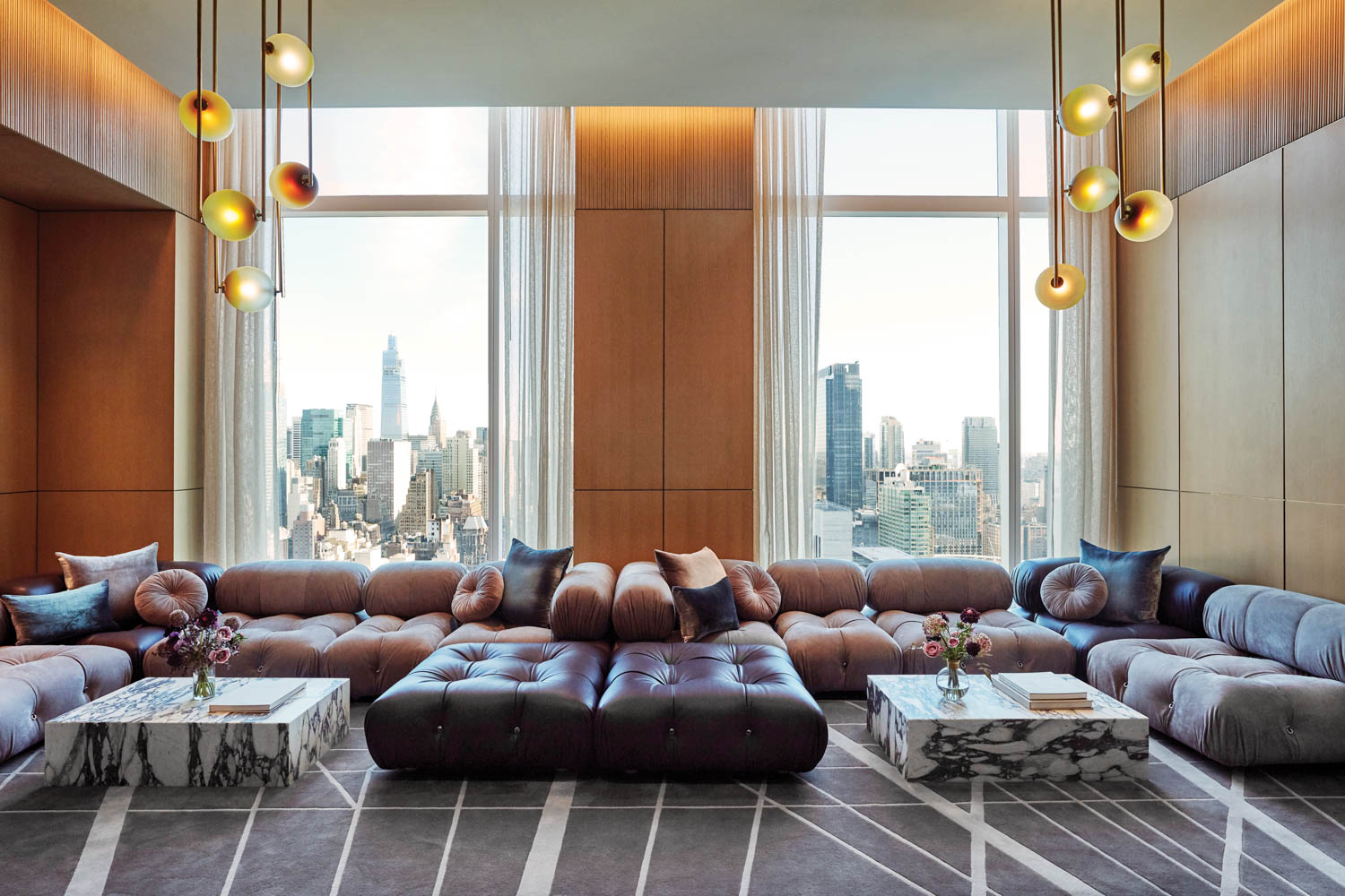 Mario Bellini sofas provide seating in the common area of a residential building with views of NYC out the window