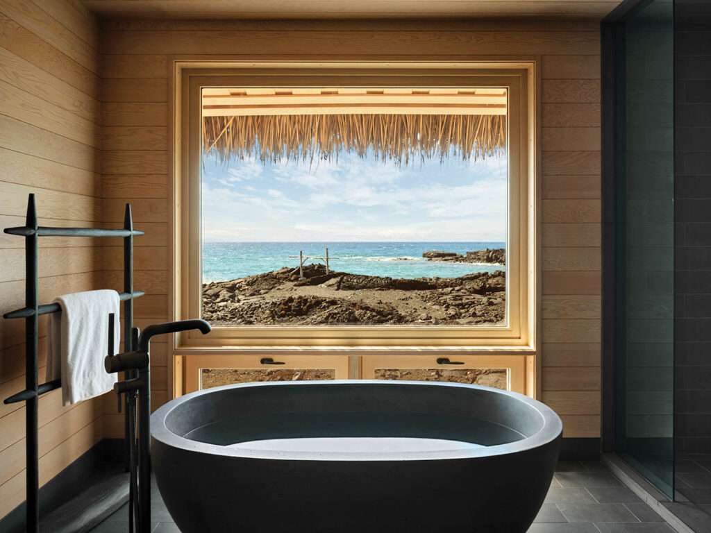 a bath­room’s stone tub with a view of a lava field