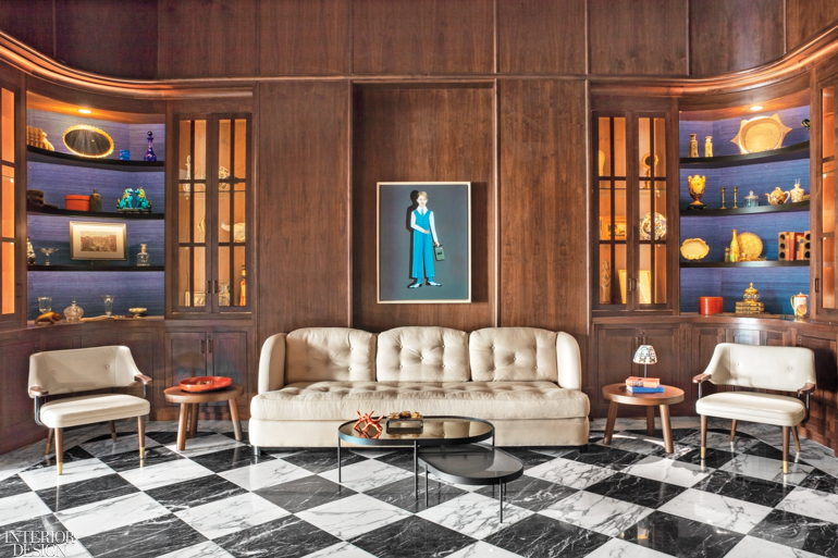 A sitting area with wood paneled walls and a black and white marble floor 