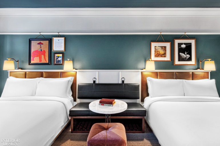 A guest room with a custom leather bench between two guest beds with white sheets