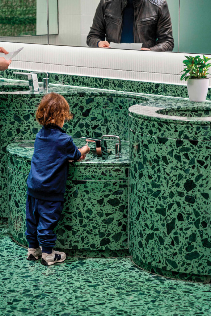 child inside green themed public restroom