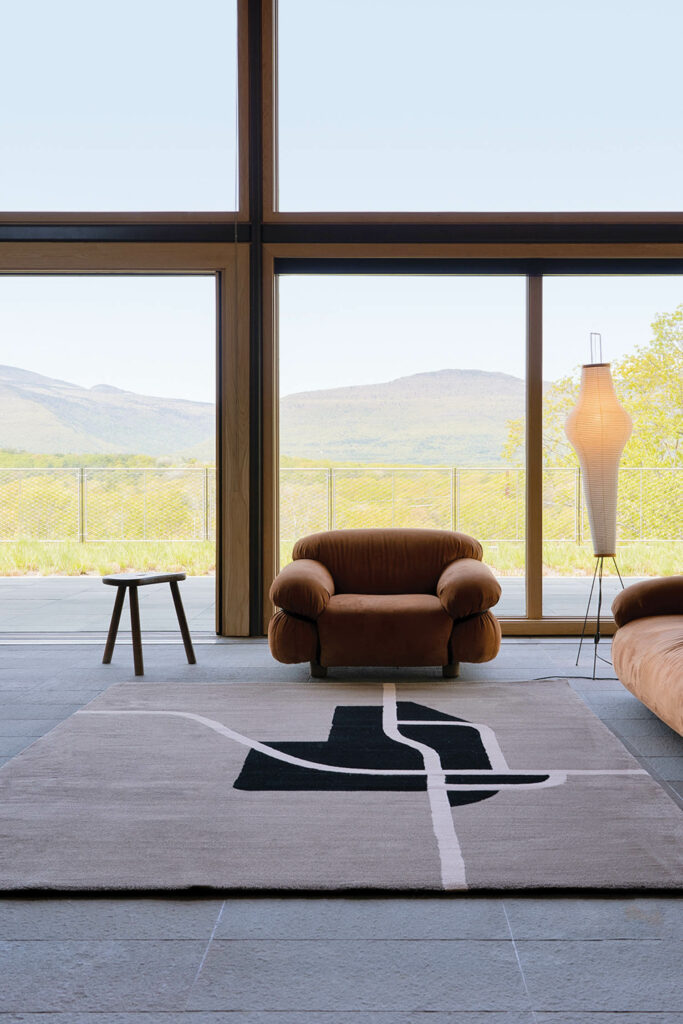 a windowed room with an area rug and armchair