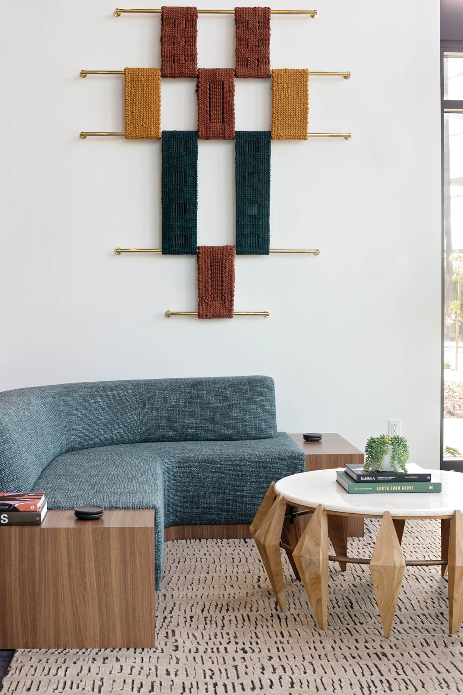 a jewel-toned art piece hangs on the wall above a blue banquette