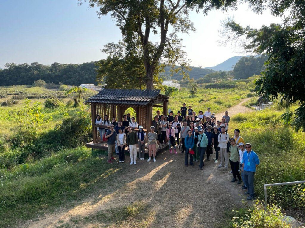 people standing in line outside for festival surrounded by greenery and mountains