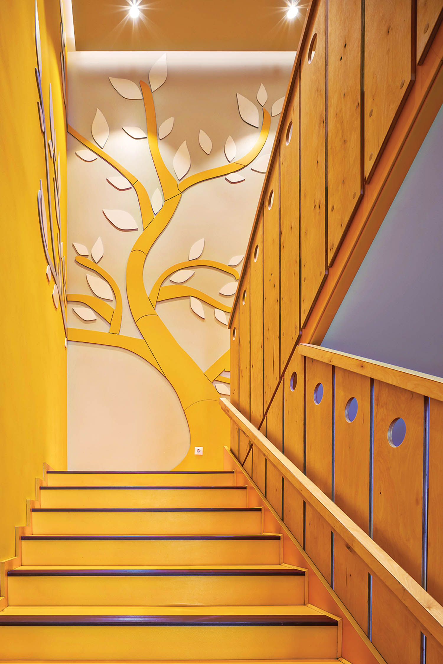 Stairway with wooden paneled stairs and walls and big tree decal