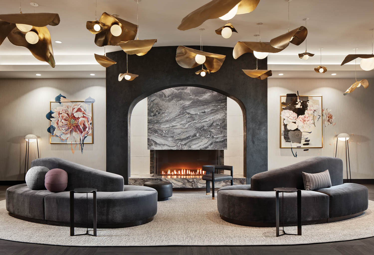 seating room area with black couches and golden lighting hanging from the ceiling