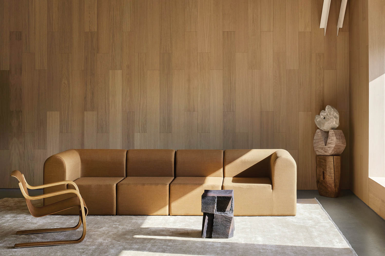 room with long brown sofa, chair and brown walls