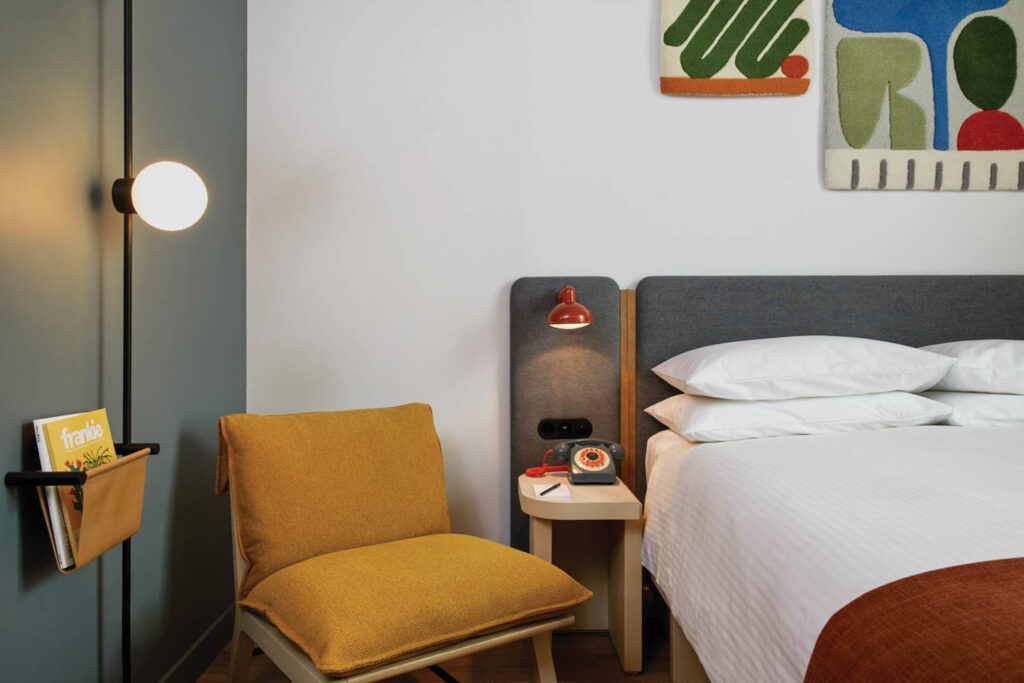 corner of bedroom with small side table and yellow chaise