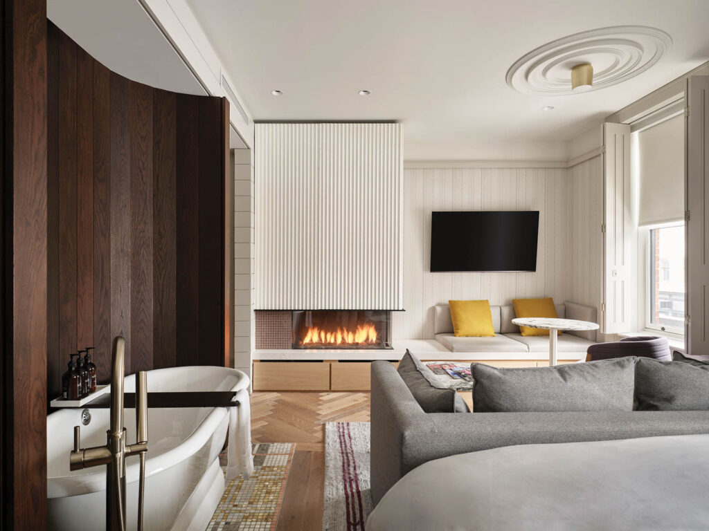 sitting room area with grey couches, fireplace and bathtub